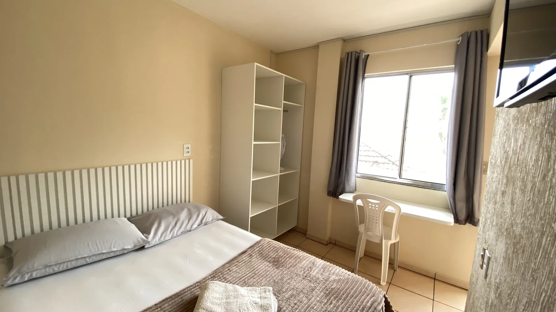 Quarto arejado com janela ampla e guarda-roupa